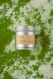 Silver cylindrical container with a beige label on a green textured background