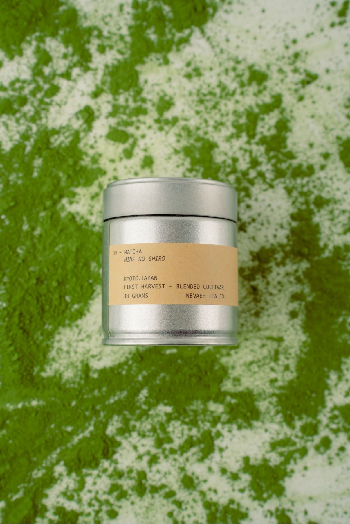 Silver tea canister with a beige label on a green and white textured background