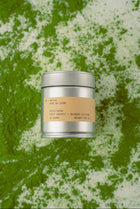 Silver tea canister with a beige label on a green and white textured background