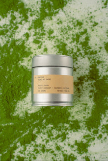 Silver tea canister with a beige label on a green and white textured background