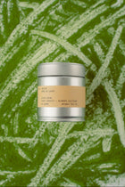 Silver tea canister with a brown label on a green background