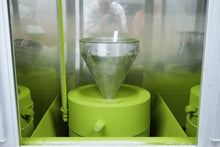 Green machine with a funnel-like component inside a transparent enclosure